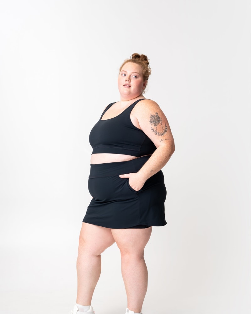Front of a model wearing a size 2X adventure performance skort in black by alder apparel. | dia_product_style_image_id:348084